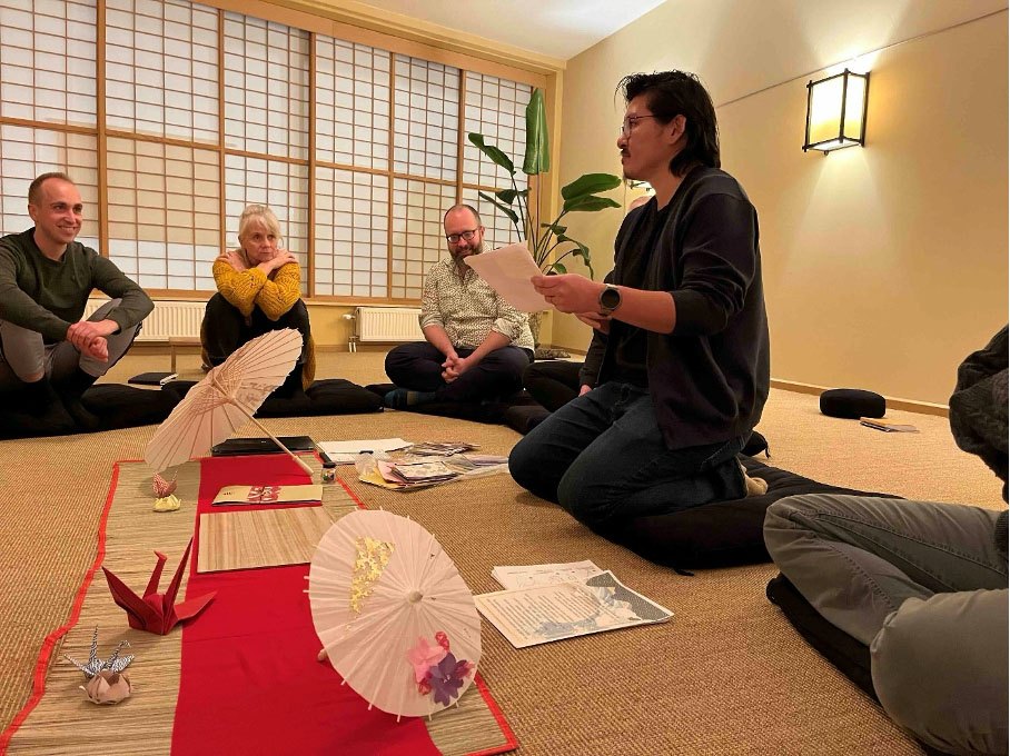 Kazuya zit geknield op de vloer van de zendo en vertelt enthousiast over origami